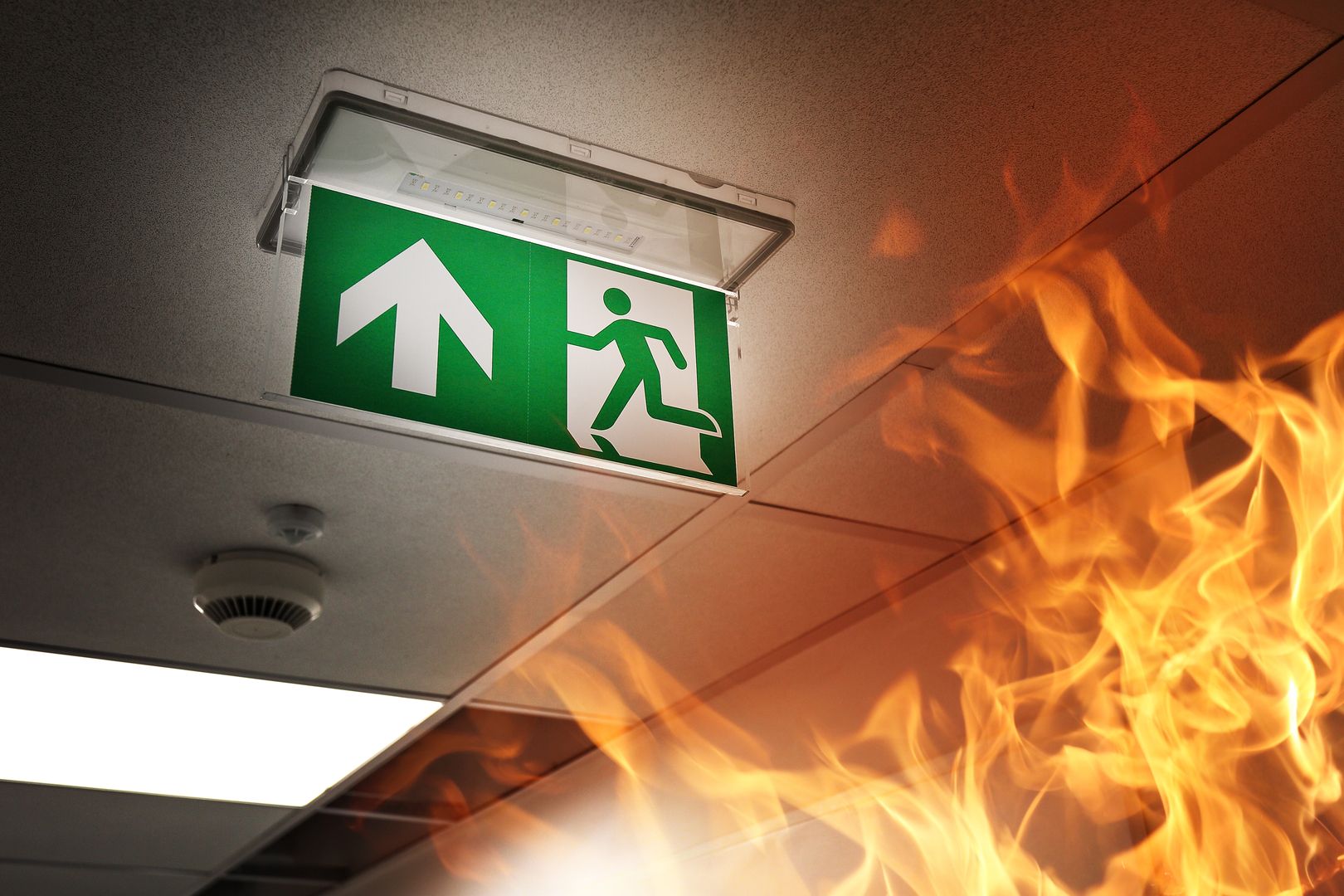 Ein Notausgangsschild in einem Gebäude während Flammen von unten rechts kommen